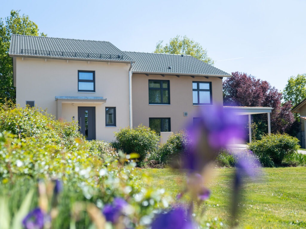 Blick über einen Garten hinweg auf ein Fertighaus