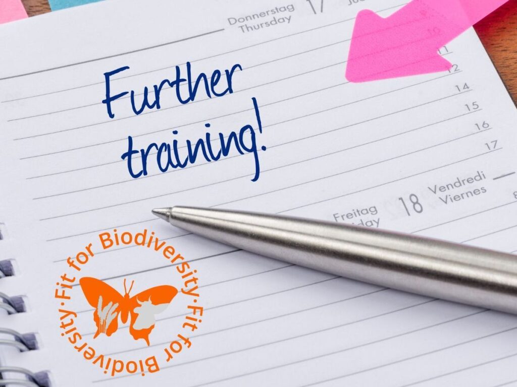 Blick in einen Terminkalender, in dem ein pinker Pfeil sowie ein Kugelschreiber auf einen Termin weisen. Im Kalendereintrag steht: "Further training!".