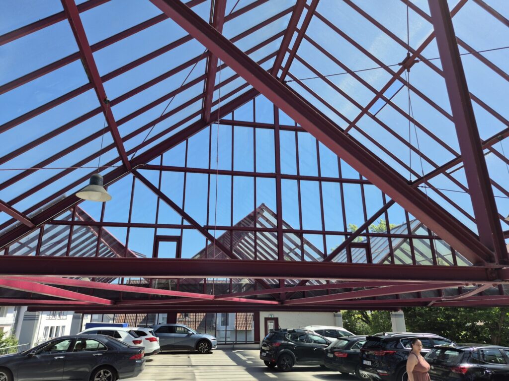 Blick nach oben auf ein verglastes Dach über einem Parkdeck.