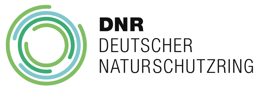 Zu sehen ist das Logo des DNR (Deutscher Naturschutzring). Es besteht aus mehreren ineinander verschachtelten Kreisen mit offenen Umrissen. Die Kreise sind in den Farben Grün, Blau und Türkis gehalten.