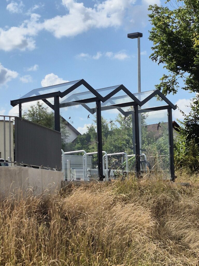 Blick auf ein Bahnwartehäuschen aus Glas.