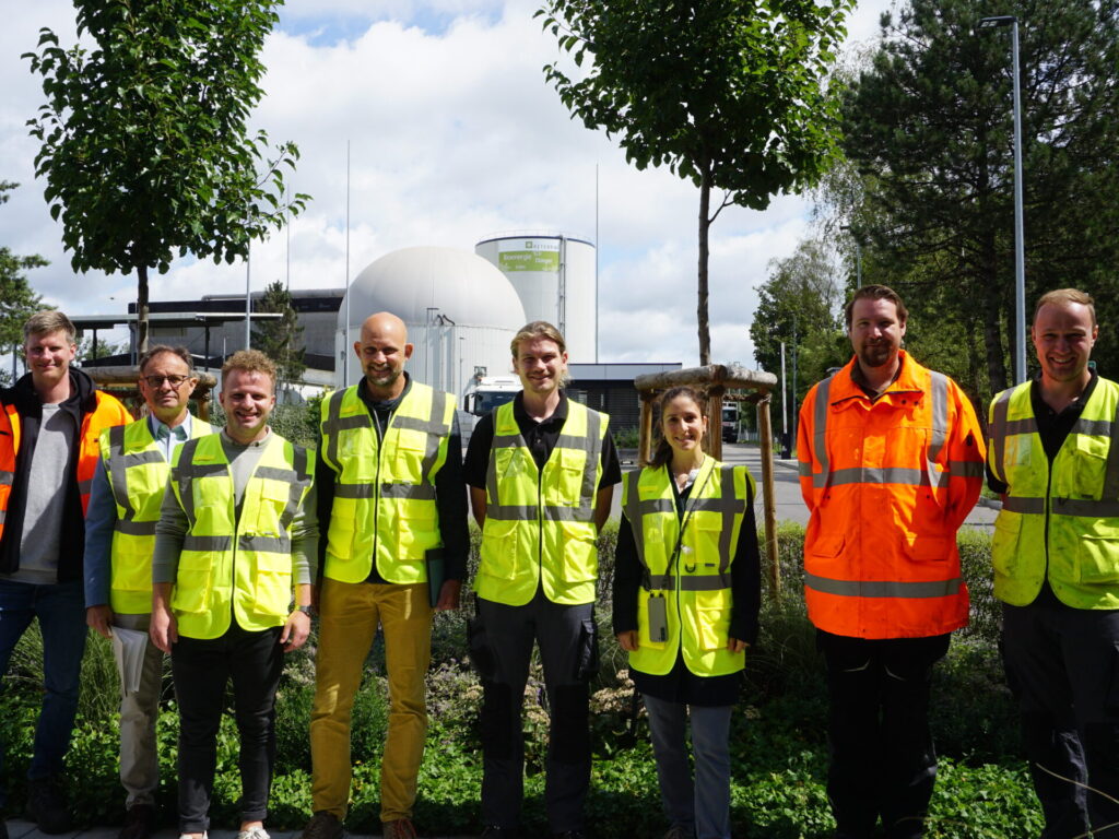 Eine Gruppe von Menschen mit leuchtenden gelben und orangenen Sicherheitswesten schaut in die Kamera.