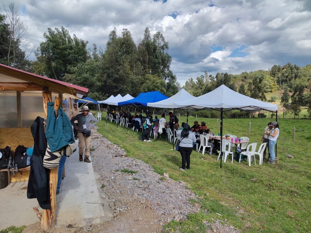 Unter Pavillonzelten stehen Tische und Stühle. Menschen sitzen unter den Zelten.