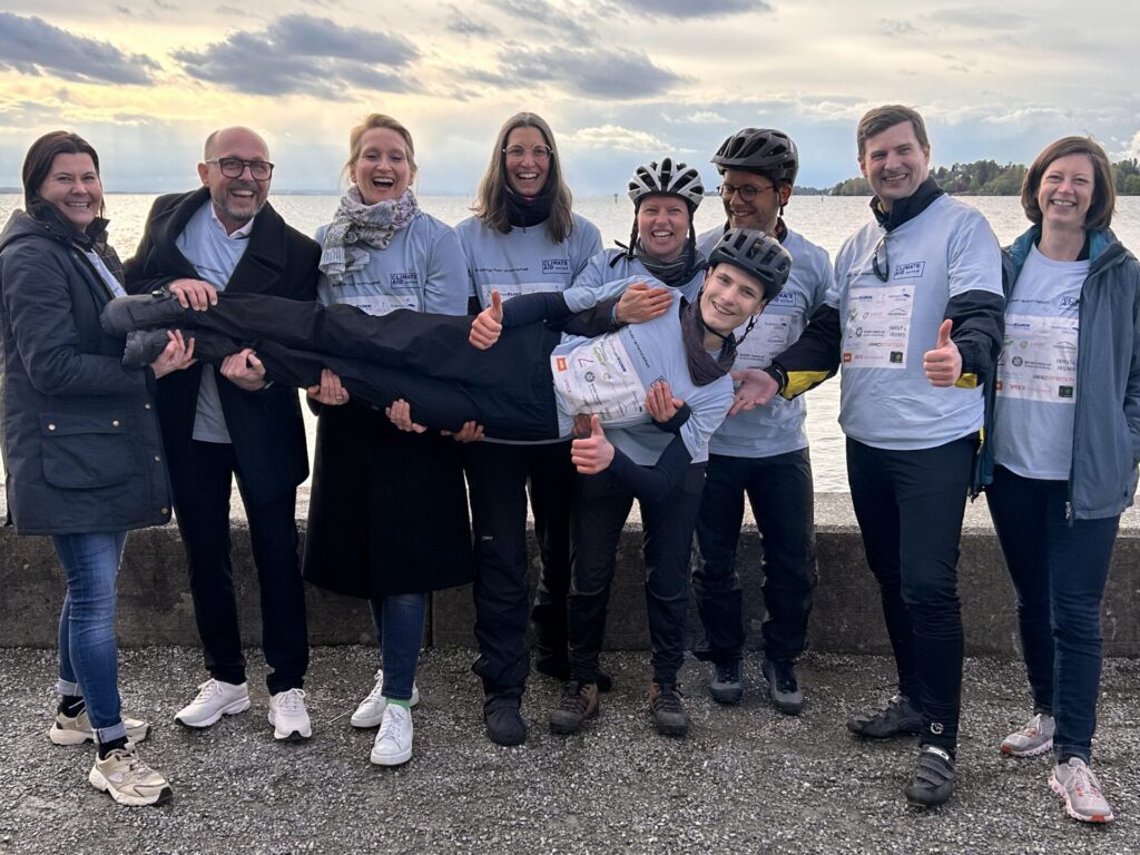 Zusehen sind 9 Personen, die den Radfahrer Leon Paasch auf Händen tragen. Alle lächeln zur Kamera.