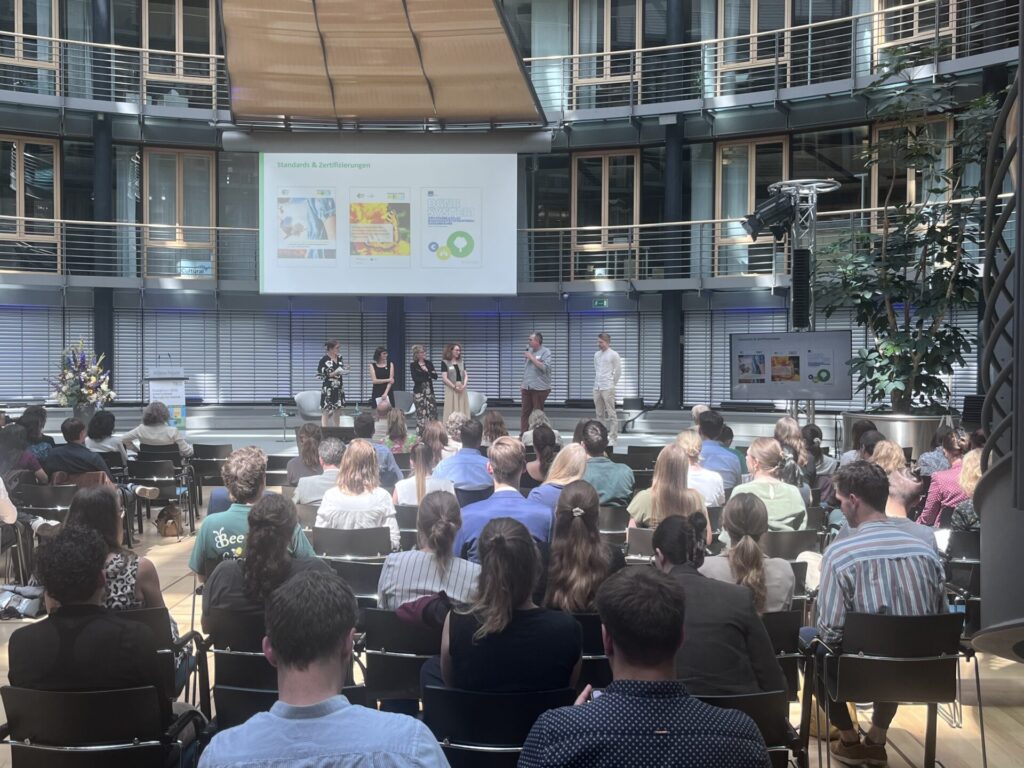Blick von hinten auf das Publikum und die Leinwand in einem Konferenzsaal.