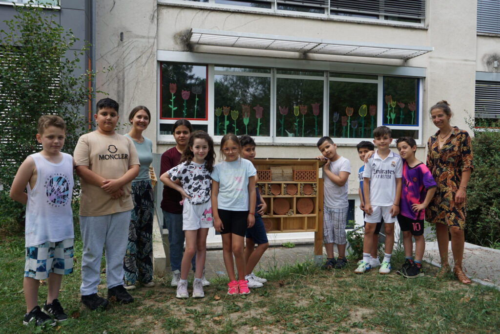 Die Schüler*innen stehen vor ihrem Insektenhotel. Rechts im Bild steht Saskia Wolf von der Bodensee-Stiftung.