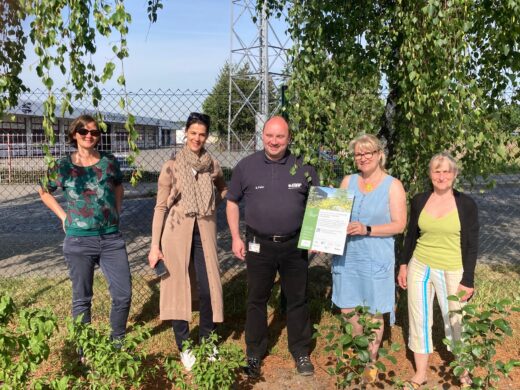 Fünf Personen stehen vor einem Baum und halten das Notice Board des Projekts in der Hand