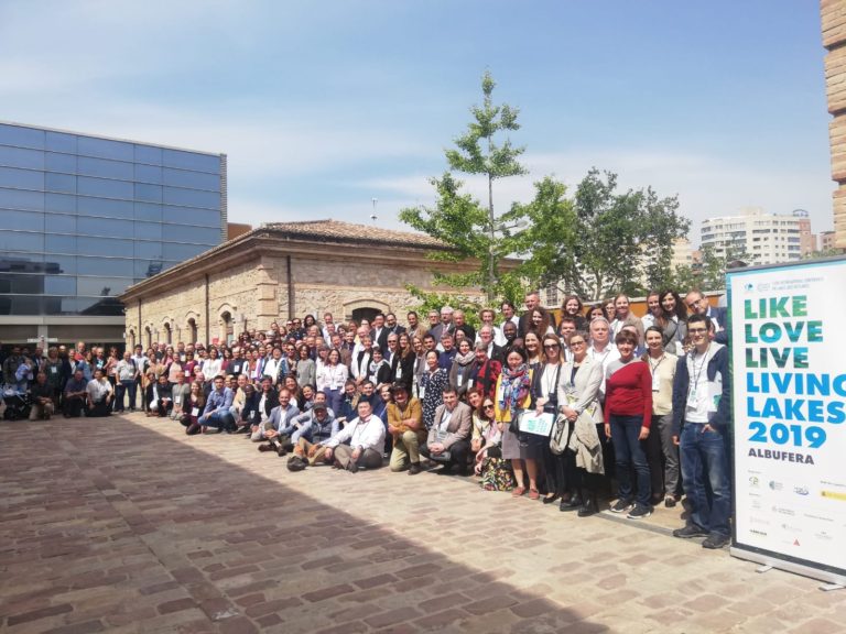 Gruppenfoto der Teilnehmenden der internationalen Konferenz „Living Lakes 2019" in Valencia (Albufera). Rund 150 Personen stehen vor einem historischen Gebäude, rechts im Bild ein Banner mit dem Konferenzmotto „Like Love Live Living Lakes".