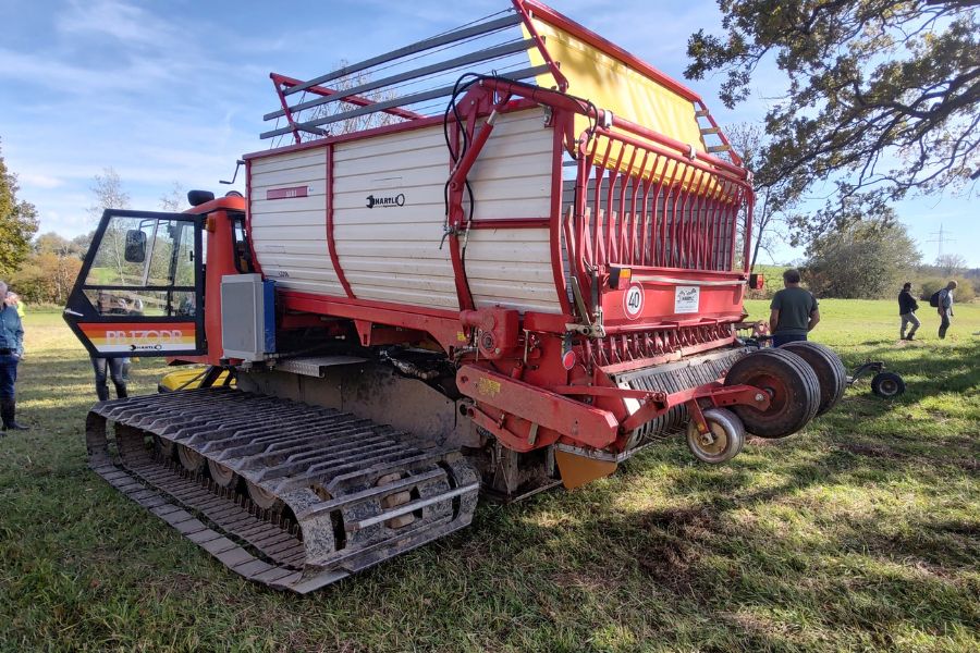 Blick auf einen landwirtschaftlichen Transportwagen, der nicht auf Reifen, sondern Kettenlaufwerken.