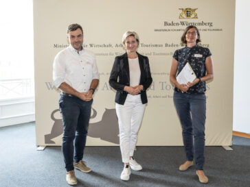 Wirtschafts- und Arbeitsministerin Dr. Nicole Hoffmeister-Kraut steht zwischen Dimitri Vedel, Schwerpunkt Energiewende, (links) und Daniela Dietsche, Schwerpunkt Biodiversität (rechts) vor einer Stellwand des Ministeriums für Wirtschaft, Arbeit und Tourismus Baden-Württemberg. ograf: Reiner Pfisterer