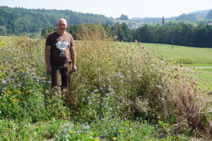 Landwirt Andreas Deyer steht inmitten eines Blühstreifens.