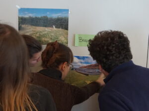 Drei Menschen stehen vor einer Wand, auf die das Foto eines Firmengeländes geklebt ist.